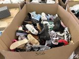 many pairs of shoes in a cardboard box on the floor