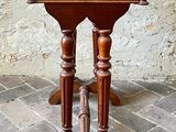 a small wooden table on a brick floor with a stone wall in the background