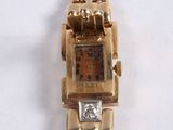 a gold wrist watch with a diamond on the face