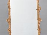 un miroir au cadre doré ouvragé posé sur un sol en damier