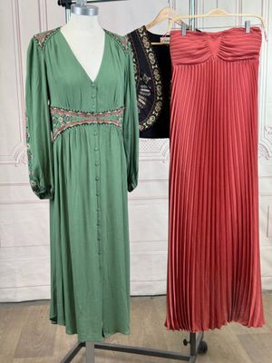 two dresses on a mannequin stand in front of a white wall