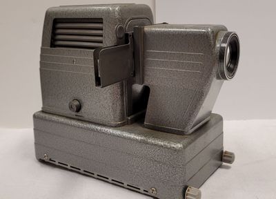 un vieux projecteur de cinéma posé sur une surface blanche