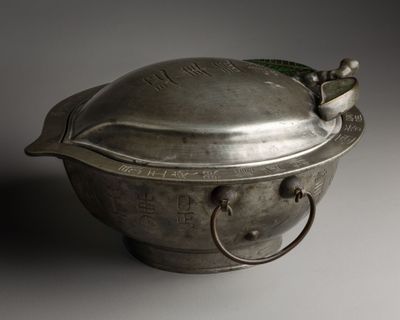 a metal bowl with a lid and handles on a table