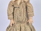 an old fashioned doll with a bonnet and dress on it ' s head