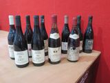 des bouteilles de vin rouge alignées sur une table devant un mur rouge