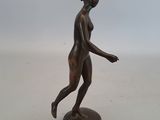 statue en bronze représentant une femme marchant, posée sur un socle rond