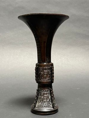 a metal vase with a design on it on a gray surface