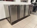 a stainless steel counter in the middle of a tiled floor