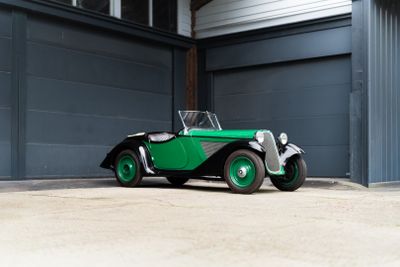 a green and black car parked in front of a garage