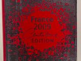 un gros plan d'un livre posé sur une surface blanche, avec une couverture rouge