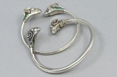 three silver bracelets with green stones on them sitting on a table