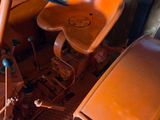 an orange tractor sitting in a garage with a steering wheel