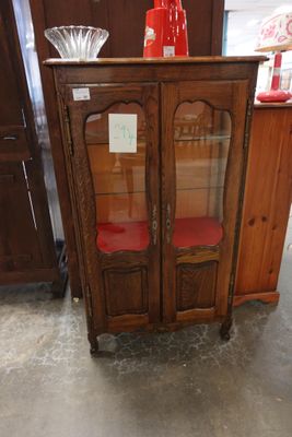 une armoire en bois avec une porte vitrée et une chaise rouge