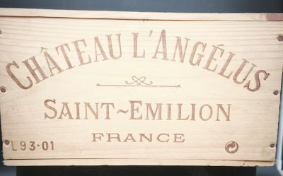 une caisse en bois sur laquelle est accrochée une pancarte indiquant « Château L'Angélus Saint-Emilio »