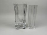une paire de vases en verre transparent posés sur une surface blanche