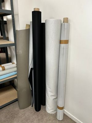 several rolls of black and white fabric sitting on top of a shelf