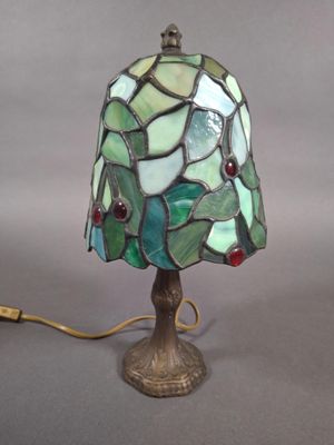 lampe avec un abat-jour en verre vert et rouge, montée sur un pied en métal