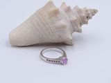 Une image représentant une bague sertie d'un saphir rose côtoie un coquillage