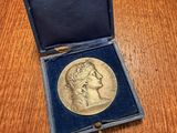 a gold medal in a blue case on a wooden table