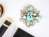 a picture of a woman ' s accessories including a watch, bracelet, broochet, and a broochet