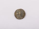 une vieille pièce de monnaie sur laquelle figure une croix, posée sur une surface blanche