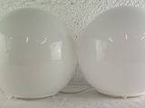 two large white eggs sitting on a white surface