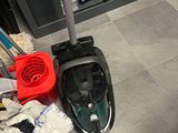 a vacuum that is sitting on the floor next to a pile of cleaning supplies