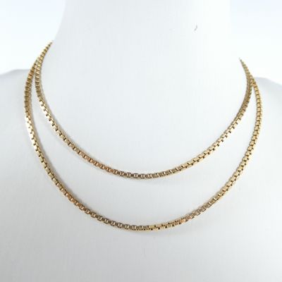 un gros plan sur un collier à chaîne en or porté par un mannequin