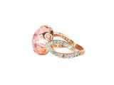 a close up of a ring with a pink stone and blue diamonds