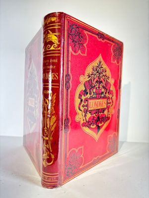 an old red book sitting on top of a table next to a white wall