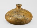 a gold vase that is sitting on a white surface
