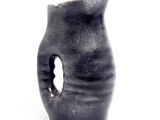 a black vase with a hole in it on a white surface