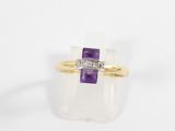a close up of a gold ring with a purple stone and a diamond