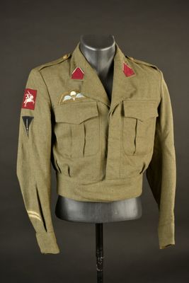une vieille veste militaire posée sur un mannequin, sur fond noir