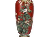 a red vase with a bird and flowers on it