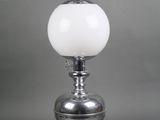 a silver table lamp with a white glass shade on top of it