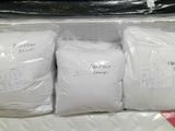 three bags of white pillows sitting on top of each other