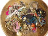 un bol en bois rempli de nombreux bijoux, posé sur une table