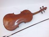 an old violin sitting on top of a white surface next to a stick