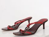 red and black leather sandals with red straps on a white surface