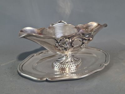 une assiette ancienne en argent, sur laquelle repose une soucoupe en argent