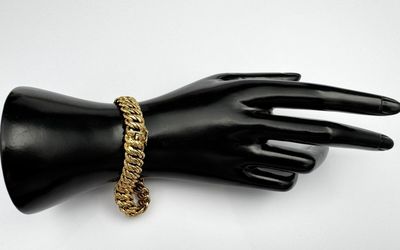 a close up of a mannequin hand with a gold chain bracelet