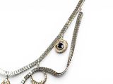a silver necklace with a black stone and a pair of scissors on a white background