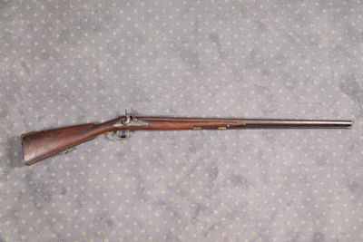 un vieux fusil au canon en bois posé sur un drap à pois