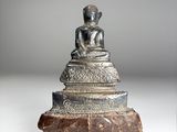 une image représentant une statue d'une personne assise sur un rocher