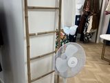 wooden ladder leaning against a wall with a fan in front of it