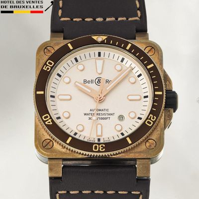 a gold and black watch with a white dial