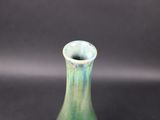 a small green vase sitting on a black surface