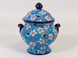 un vase bleu orné de fleurs, posé sur une surface blanche