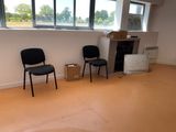 two black chairs in the corner of a room with a fire place
